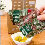 Unboxing video of 24 pack variety box. Bag is torn open revealing vibrant cracked green olives.