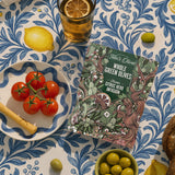 overhead image of a citrus herb bag on a table surrounded by olives, tomatoes, lemonade cup