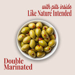 image of a plate of whole green olives with crushed peppers, with text saying "with pits inside like nature intended" and "double marinated" with teta's olives logo