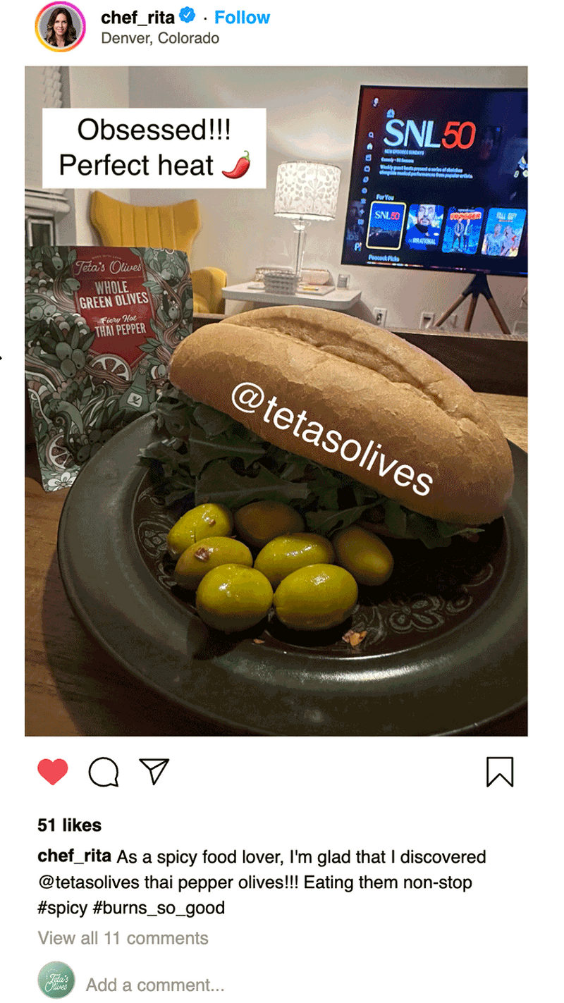 Sandwich with olives on a plate, with a TV screen in the background displaying 'SNL 50'.