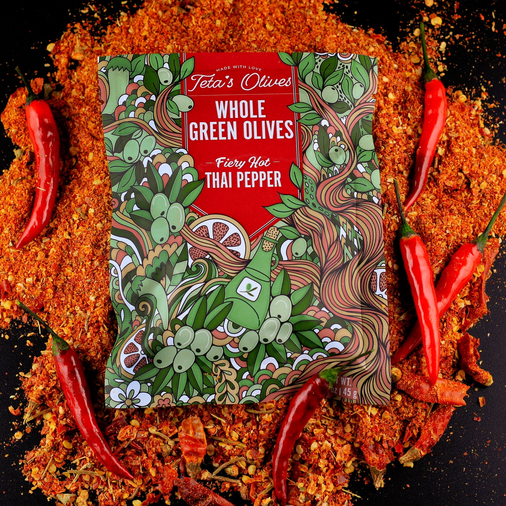 image of a bag of teta's olives fiery hot thai pepper laying on a bed of crushed red peppers, surrounded by red thai peppers