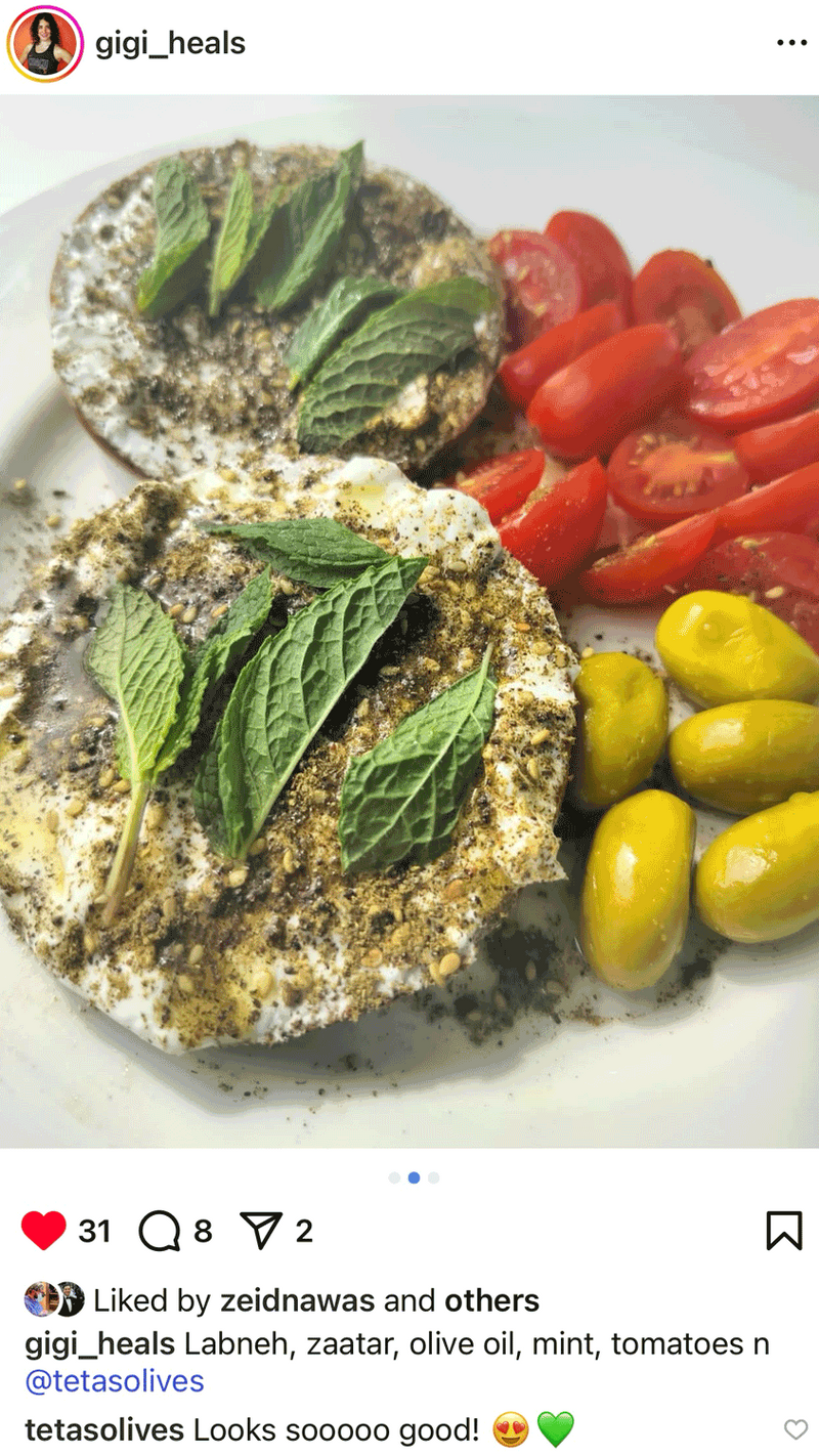 Plated dish with labneh, za'atar, olives, and tomatoes on a white plate.