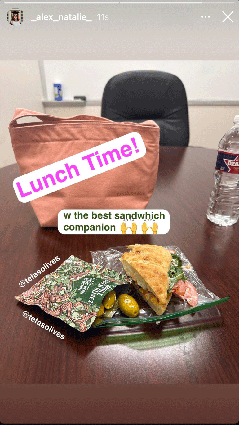 Lunchtime scene with a sandwich, bag, and water bottle on a table.