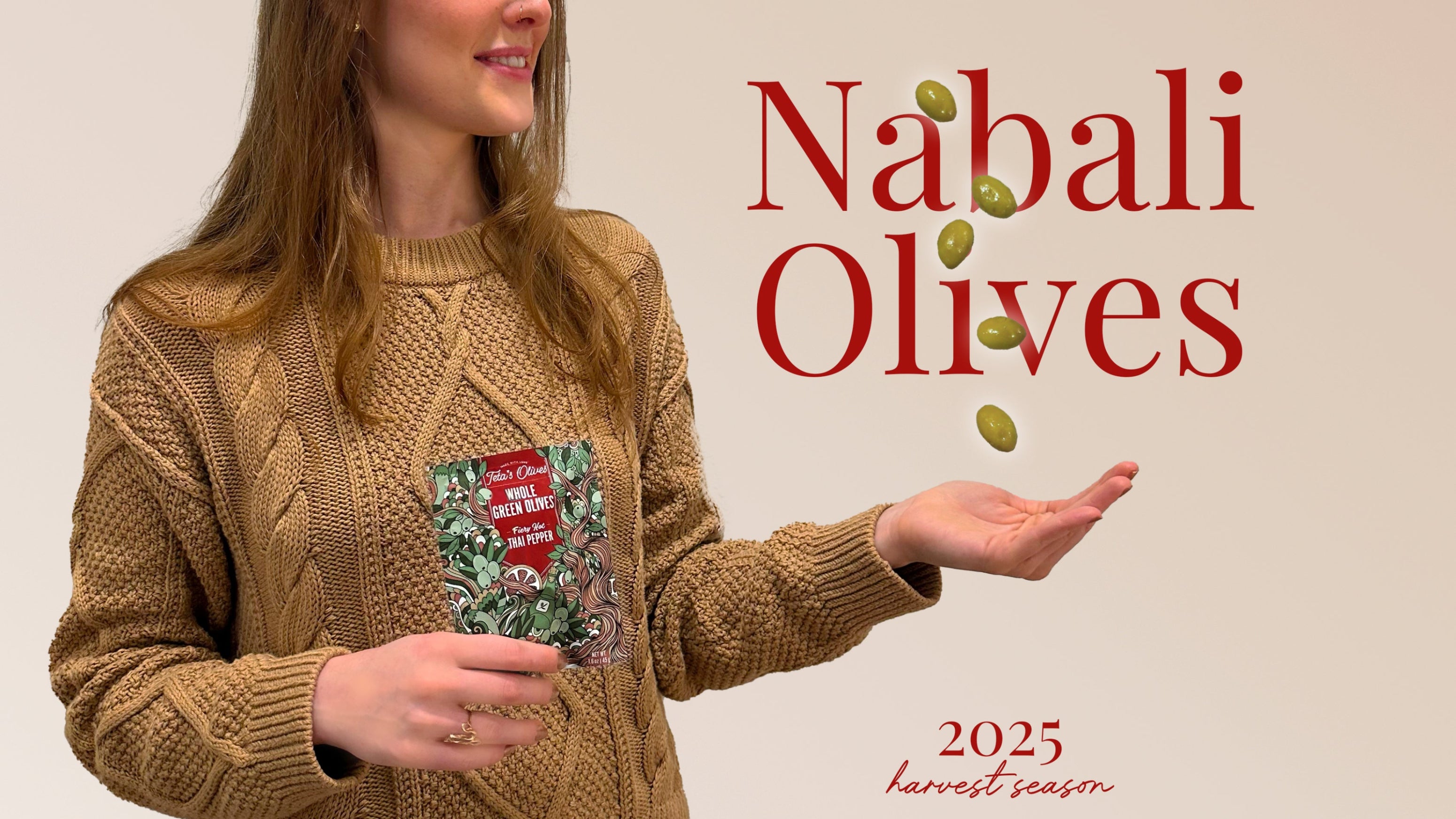 Attractive woman holding a bag of Teta's Olives Thai Pepper flavor. Palm of her hand is open with 5 cracked green olives floating in the air. 