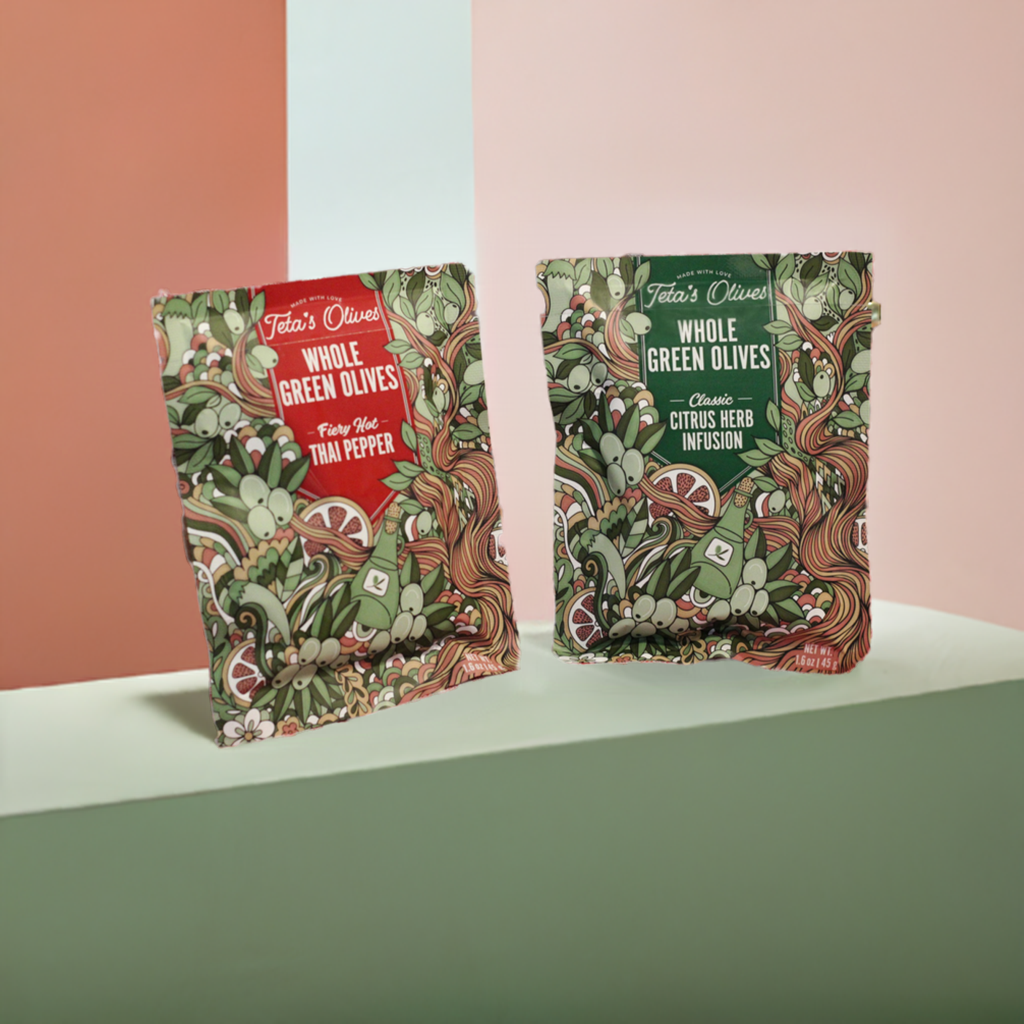 2 bags of teta's olives snack bags (classic citrus herb infusion and fiery hot thai pepper), against a multi-color pastel background, front view, close up
